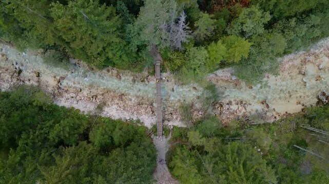 Aerial view of river, forest, and bridge with man walking in Triglavska Bistrica, Kranjska Gora, Slovenia.