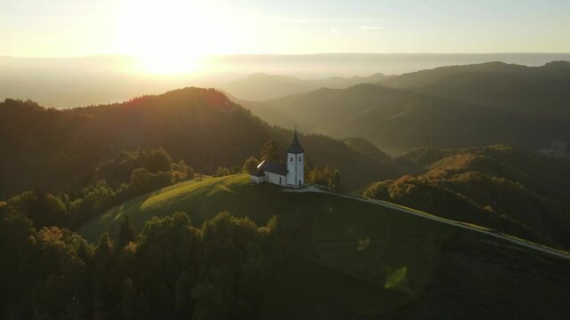 Aerial view of St. Primoz church at sunrise with Julian Alps peaks, Jamnik, Slovenia.