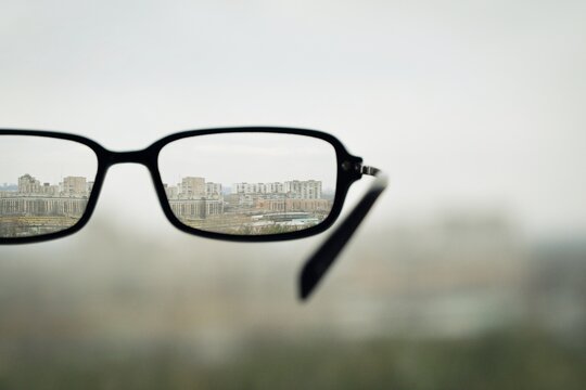 Bad eyesight. Selective focus image of unfocused eyeglass and sharp cityscape in the background.