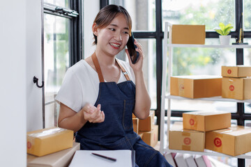 Starting small businesses SME owners asian female entrepreneurs call phone on receipt box and check online orders to prepare to pack the boxes, sell to customers, SME business ideas online.
