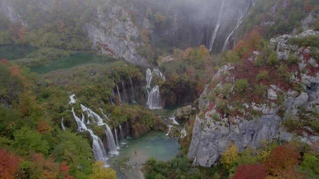Aerial view of misty waterfall cascading into serene lake in Plitvice National Park, Lika-Senj, Croatia.