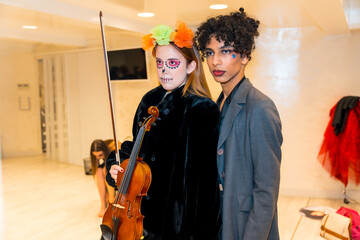 Two women are posing for a photo, one of them holding a violin