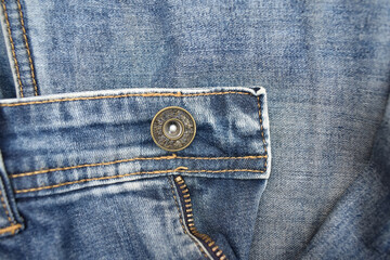 A closeup picture of a faded light blue jeans pant with button. Clothing industry theme