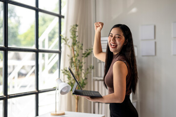 A woman is holding a laptop and smiling