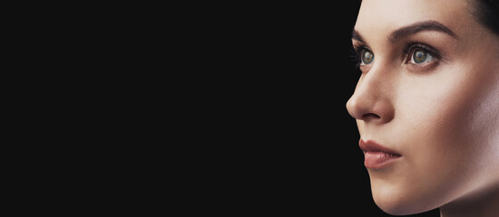 A close-up shot of a womans profile against a dark background. She is looking off to the side with a serious expression. © Prostock-studio