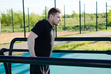 Obraz premium Caucasian male athlete doing pull-ups on the horizontal bar outdoors in a summer park