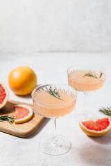Elegant grapefruit and rosemary cocktails served in crystal glasses with fresh grapefruit slices,...