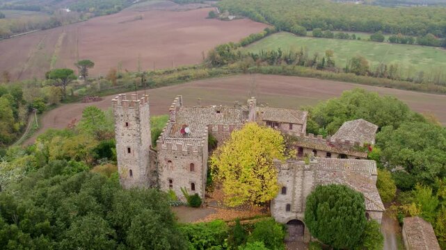 Aerial view of medieval castle surrounded by greenery and fields, Castello di Montalto, Tuscany, Italy.
