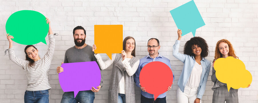 Global communications. Group of happy young diverse people holding empty colorful speech bubbles and smiling at camera