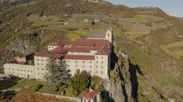 Aerial view of Monastero di Sabiona monastery surrounded by Dolomite mountains in autumn, Chiusa, South Tyrol, Italy.
