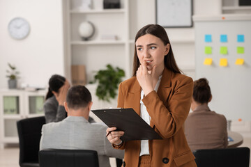 Woman with clipboard feeling embarrassed during business meeting in office