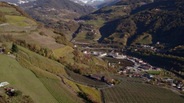 Aerial view of vineyard and farm nestled in the Dolomites mountain range during autumn, Chiusa, South Tyrol, Italy.