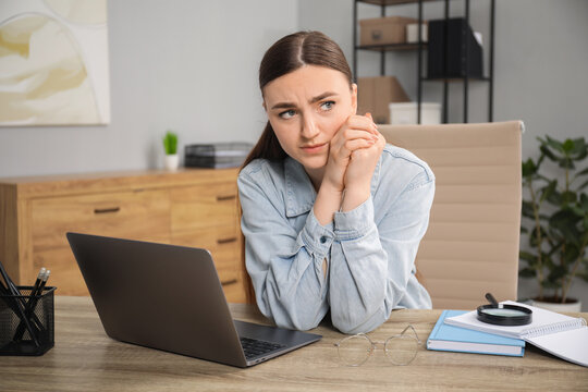 Embarrassed woman at wooden table with laptop in office