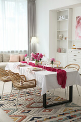 Beautiful table setting with pink accent and rattan chairs in dining room
