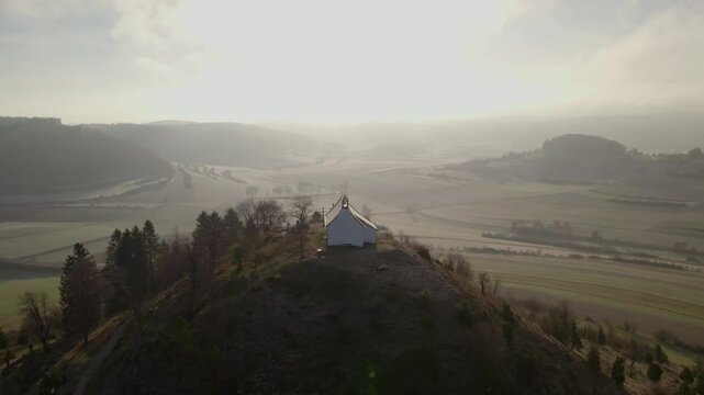 Aerial view of scenic hilltop church overlooking misty valley and fields, Burladingen, Baden-Wurttemberg, Germany.