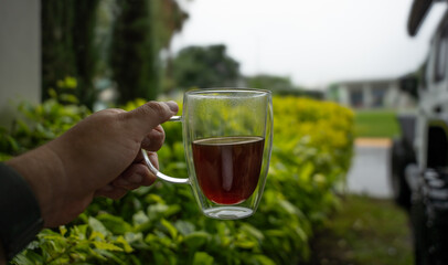 Mano con una taza de café en una tarde lluviosa