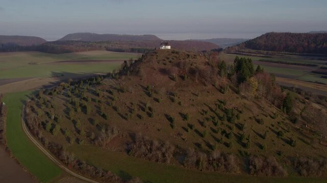 Aerial view of scenic church on hill surrounded by lush trees and valley, Burladingen, Baden-Wurttemberg, Germany.