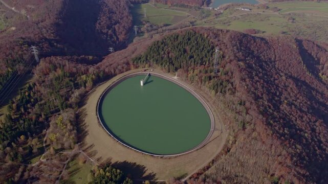 Aerial view of autumn water storage bassin with forest and mountain, Eningen unter Achalm, Baden-Wurttemberg, Germany.