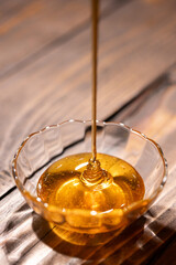 Fresh floral honey is poured into a glass bowl