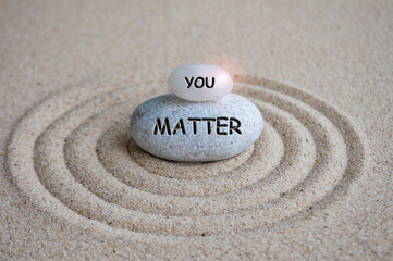 You matter text engraved on Zen stone on sand with light shining. Motivational and inspirational...