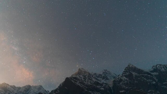 4K Night Lapse shot of Milky Way rising above the snowy Himalayan mountain peaks during the full moon night as seen from Khangsar Village in Lahaul, Himachal Pradesh, India. Night lapse background.