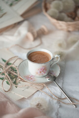 A cup of coffee on the table, flowers and a book
