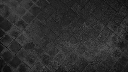 Fototapeta premium rough wet street pathway in grid pattern for design, top view. cobble dark black granite stone, square shape in grid on the outdoor pathway. sidewalk texture made of stone tiles.