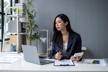 A woman is sitting at a desk with a laptop and a calculator