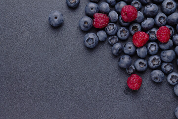 blueberries and raspberries on a blue background, a copy of the space