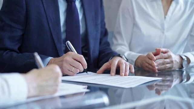 Business people wearing suits signing important documents during a corporate meeting. Win-win concept
