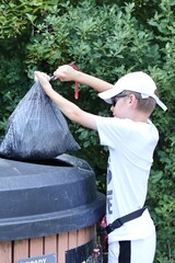 A boy throwing garbage into a garbage can © Gosia