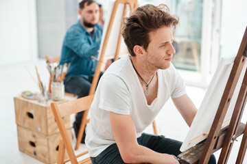 Student, man and painting in art class with canvas for university project, inspiration or education. Workshop. talent and male artist person with easel for relax, watercolor or creativity in studio