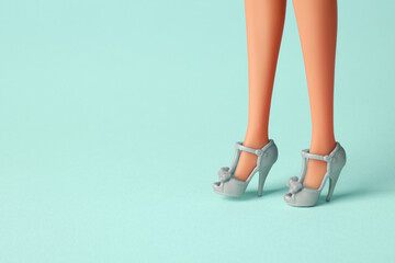 Doll's legs with fancy shoes on turquoise background. Space for text