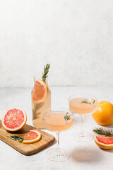 Refreshing grapefruit rosemary lemonade, served in crystal glasses on white table background....