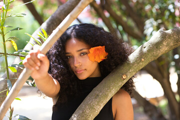 portrait of a beautiful young Latin woman with large, dark eyes and curly hair. The girl wears an...