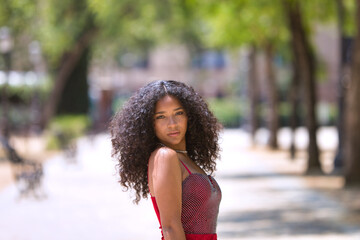 portrait beautiful young latin woman with big eyes and brunette with curly hair wearing a red dress...