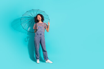 Photo of positive girl with umbrella point finger up empty space isolated cyan color background © deagreez