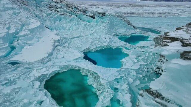 A birds eye view of an alpine glacier reveals intricate crevasses and blue meler pools hidden ast the frozen landscape.
