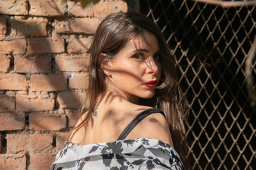 Chica latina hermosa posando en sombras junto a un muro de ladrillos