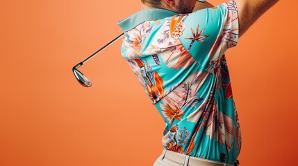 A golfer wears an eye-catching Hawaiian shirt as he swings his golf club confidently against a vibrant orange background, capturing the fusion of sport and style.