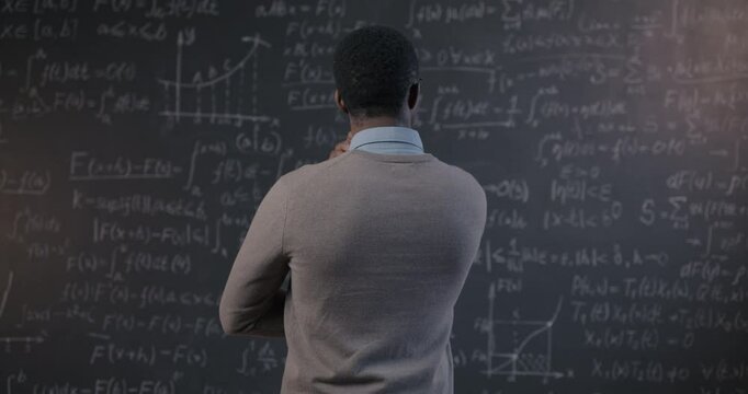 Back view of brilliant African American scientist thinking looking at chalkboard with formula in research center. Science development and education concept.