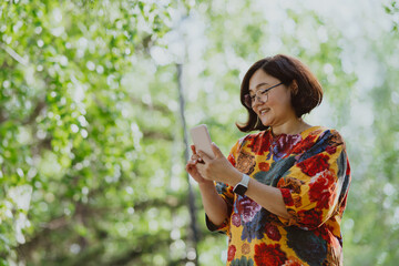Business lady, woman professional talking on mobile while enjoying nature. Happy adult woman talking on the phone while walking in the park