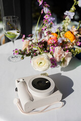 white polaroid camera and bouquet of flowers on white tablecloth covered table at summer wedding reception