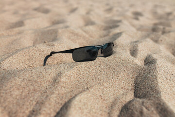 Sunglasses on the sandy beach on a sunny day. Summer vacation concept.