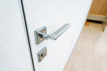 A closeup view of a door handle on a white door highlights the intricate design and features. The image showcases the beauty of the wood and the craftsmanship of the handle