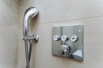 High-end shower system featuring a sleek handheld shower head and a stylish chrome control panel...