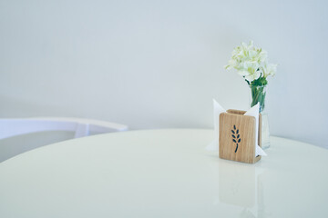 A round white tabletop in close-up with space for copying, in the background a vase with white flowers. High quality photo