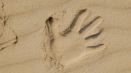 A handprint in the sand symbolizes childhood memories and summer vacations at the beach