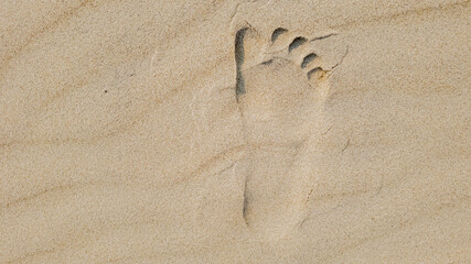 A single footprint in the sand represents a summer beach holiday, evoking relaxation and solitude
