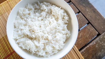 A bowl of freshly cooked white rice on a rustic wooden table, perfect for Asian cuisine and comfort food concepts